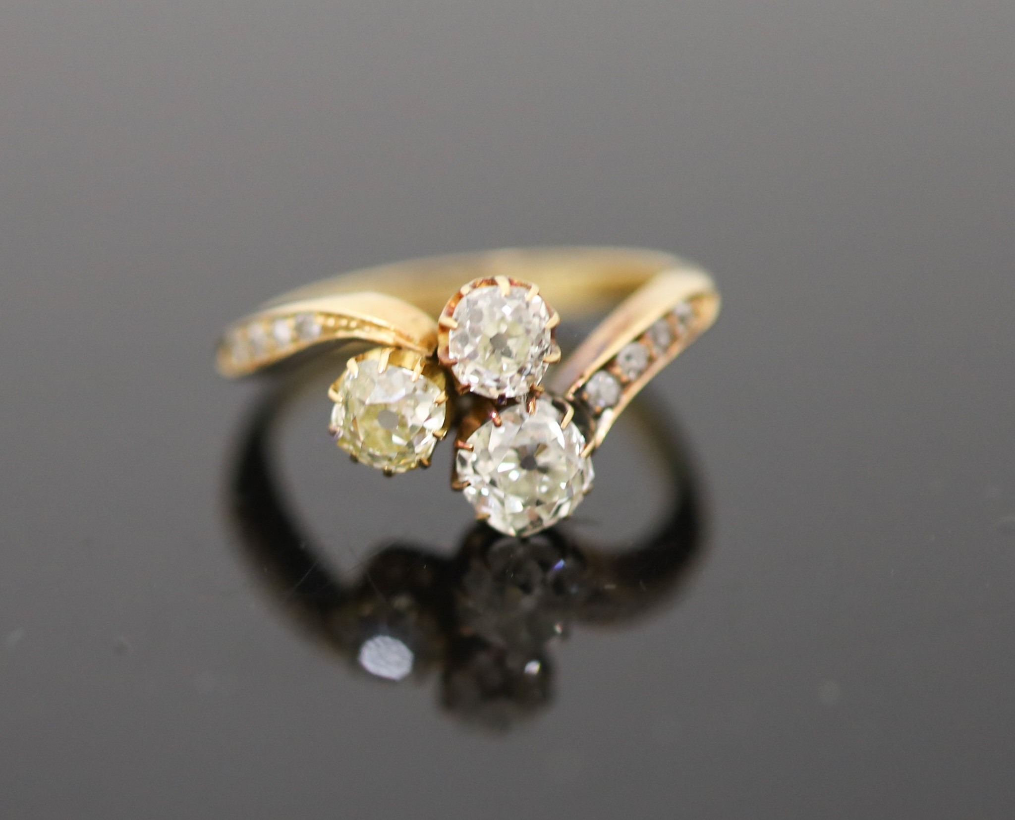 An Edwardian 18ct gold and three stone set clover shaped cluster ring